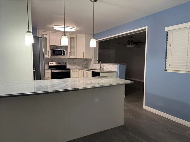 a kitchen with stainless steel appliances a sink a microwave a refrigerator and white cabinets