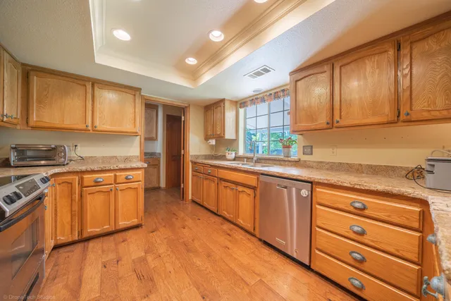 a kitchen with granite countertop wooden cabinets stainless steel appliances a sink and a window