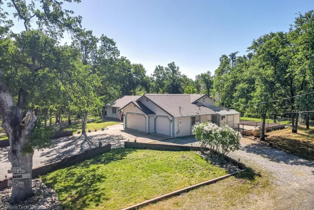 an aerial view of residential house with outdoor space and trees all around