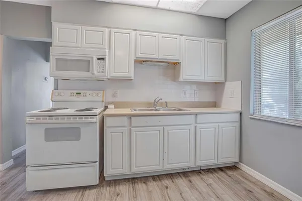 a kitchen with granite countertop white cabinets and white appliances