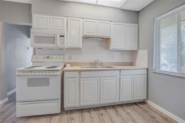 a kitchen with granite countertop white cabinets and white appliances