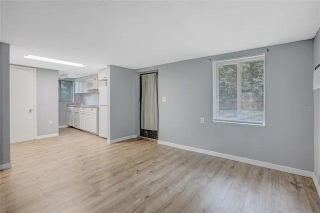 a view of an empty room with a window and wooden floor