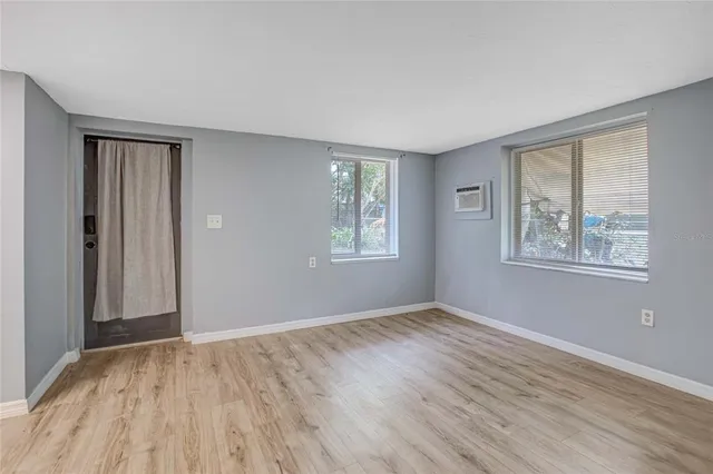 a view of an empty room with window and wooden floor