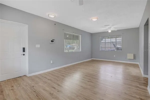 an empty room with wooden floor and windows