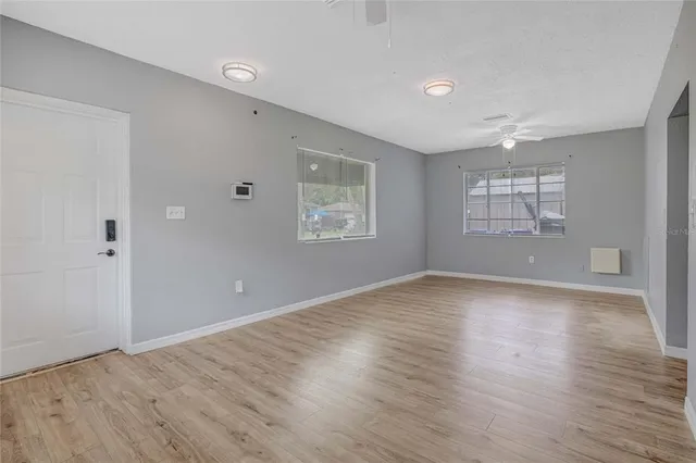 an empty room with wooden floor and windows
