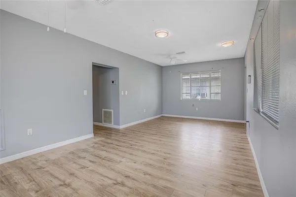 a view of an empty room with wooden floor and a window