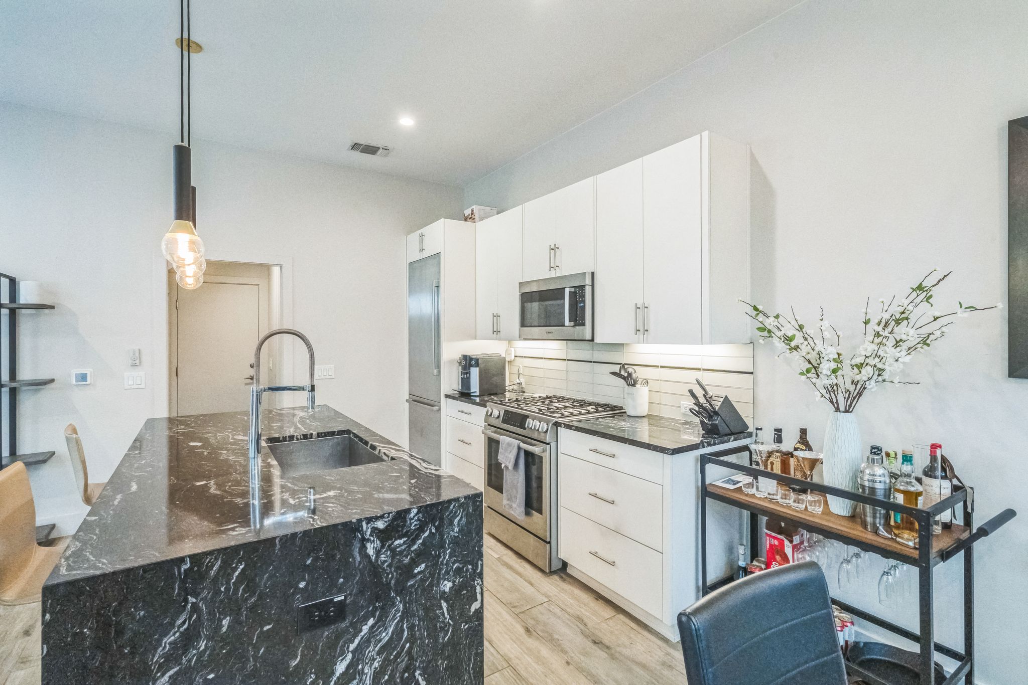 809 Bouldin Avenue Austin, TX 78704 - Photo 29 of 39 Kitchen with decorative light fixtures, stainless steel appliances, dark stone counters, decorative backsplash, and white cabinetry