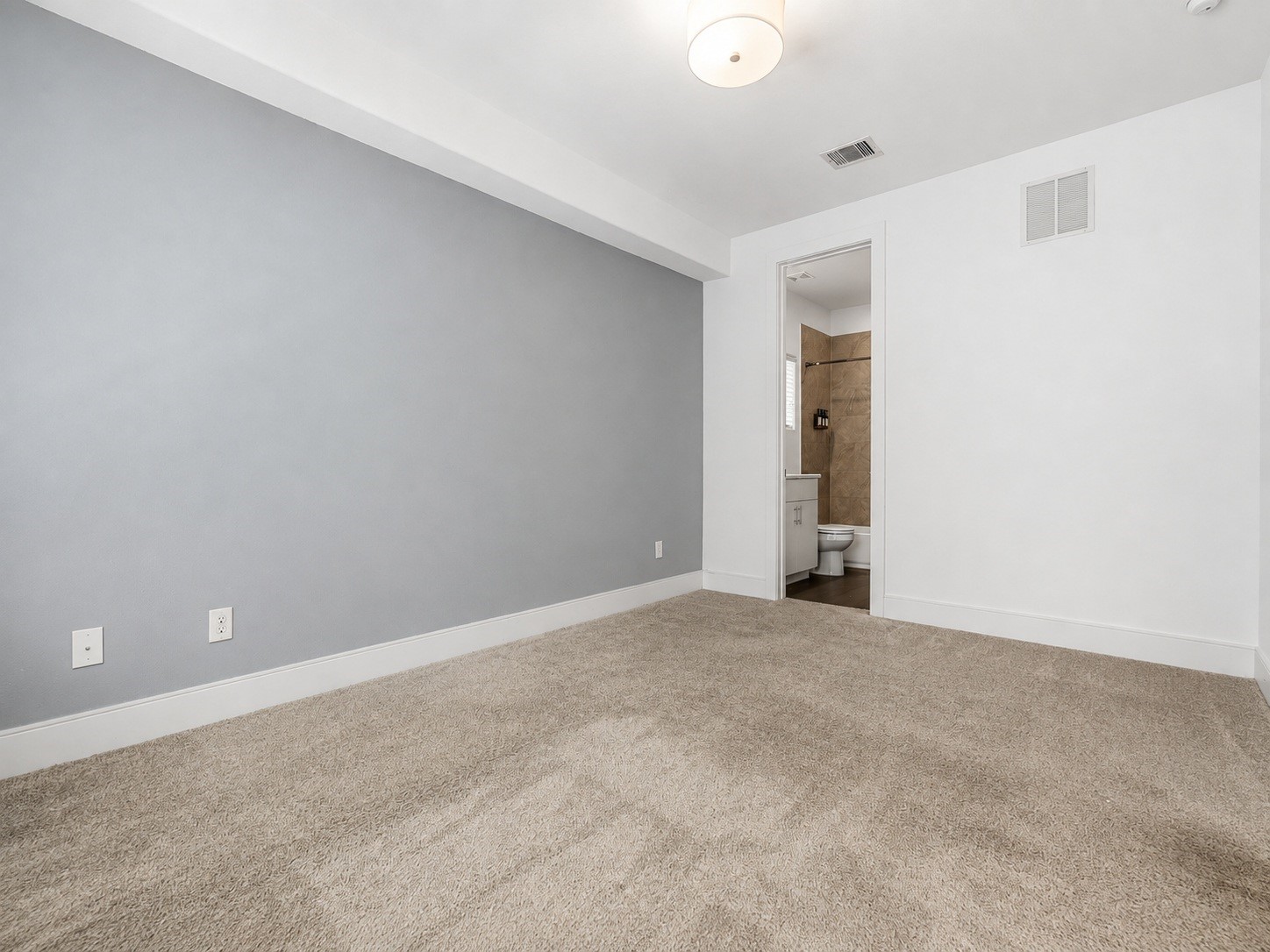 2624 Rusk Street Houston, TX 77003 - Photo 5 of 30 Spacious bedroom with plush carpeting and soft gray accents, featuring an en-suite bathroom for added convenience.
