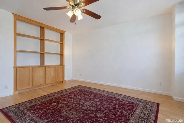 an empty room with fan and a rug