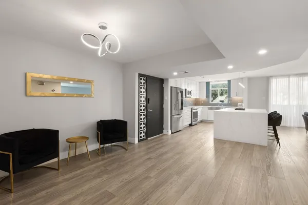 a kitchen with a stove a sink a refrigerator and a view of living room