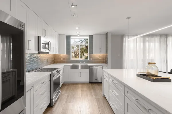 a kitchen with stainless steel appliances a dining table chairs refrigerator and cabinets