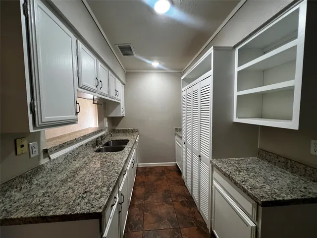 a kitchen with granite countertop sink stove and cabinets
