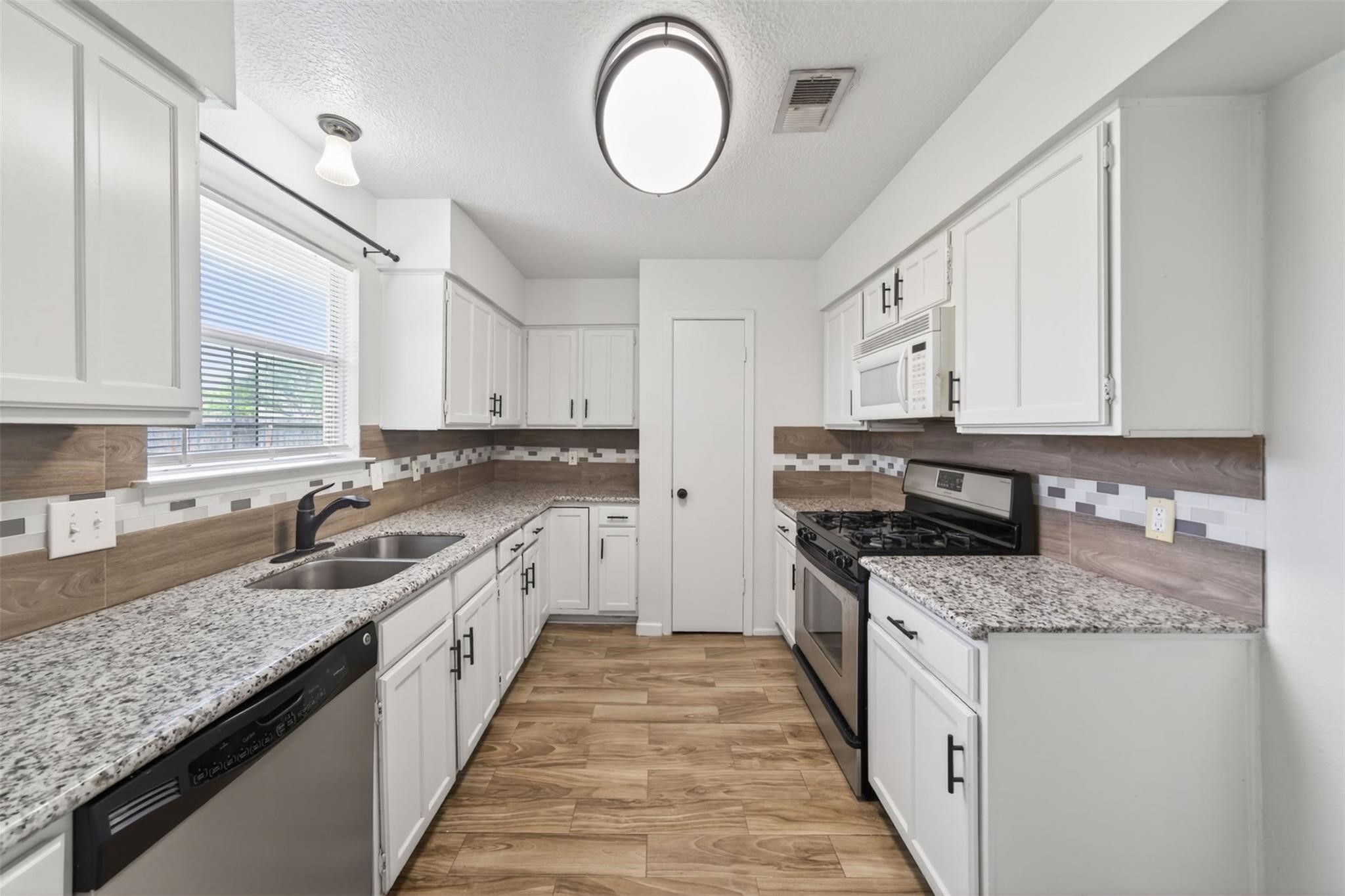 17002 Dew Drop Lane Houston, TX 77095 - Photo 7 of 24 a kitchen with granite countertop stainless steel appliances a sink stove top oven and cabinets