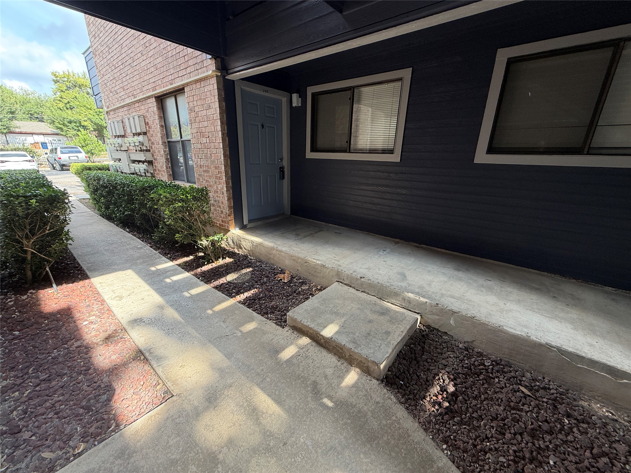 2500 Burleson Road, Unit 209 Austin, TX 78741 - Photo 14 of 15 A concrete walkway leads to a covered private entry bordered by brick and siding facades.