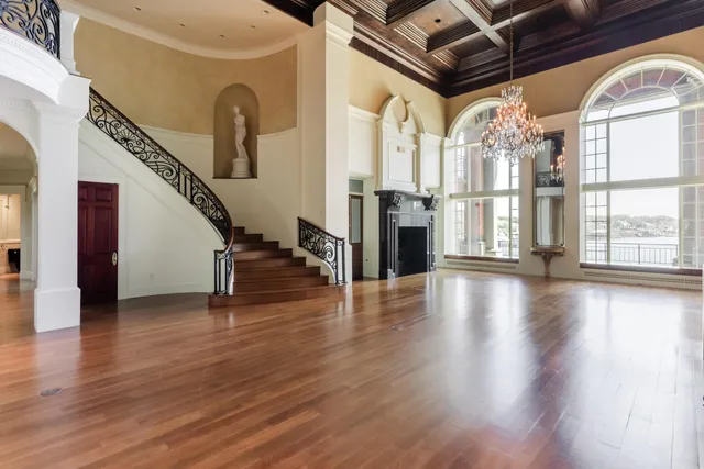 a view of a room with wooden floor chandelier and windows