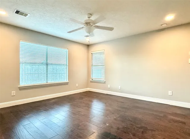 an empty room with wooden floor and windows