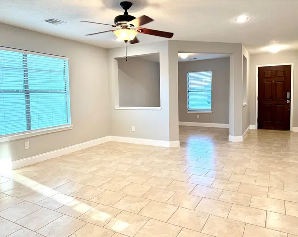 a view of an empty room with window and chandelier fan