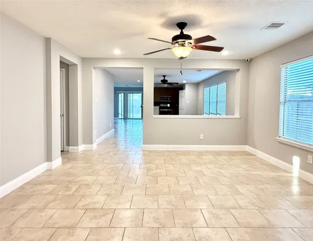 a view of an empty room with kitchen and window