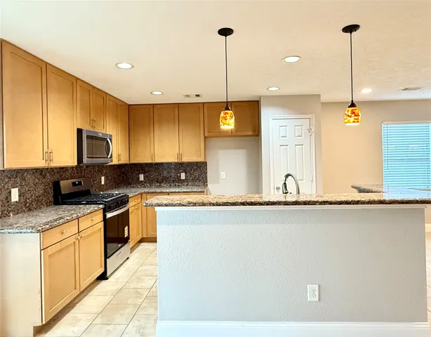 a kitchen with stainless steel appliances granite countertop a sink a stove and a wooden floors