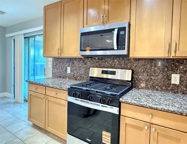 a kitchen with stainless steel appliances granite countertop a stove a sink and a microwave