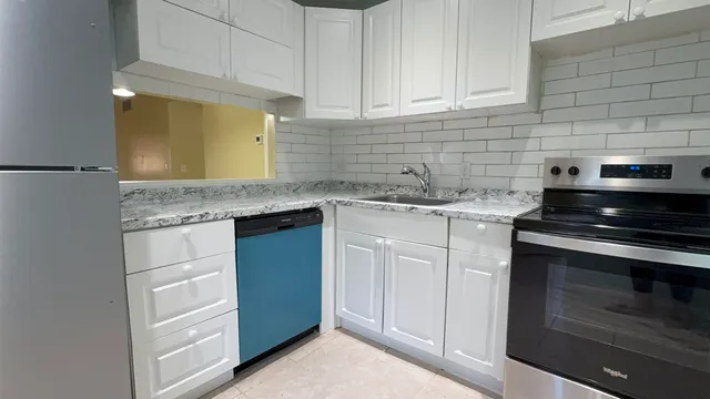a kitchen with granite countertop white cabinets and stainless steel appliances