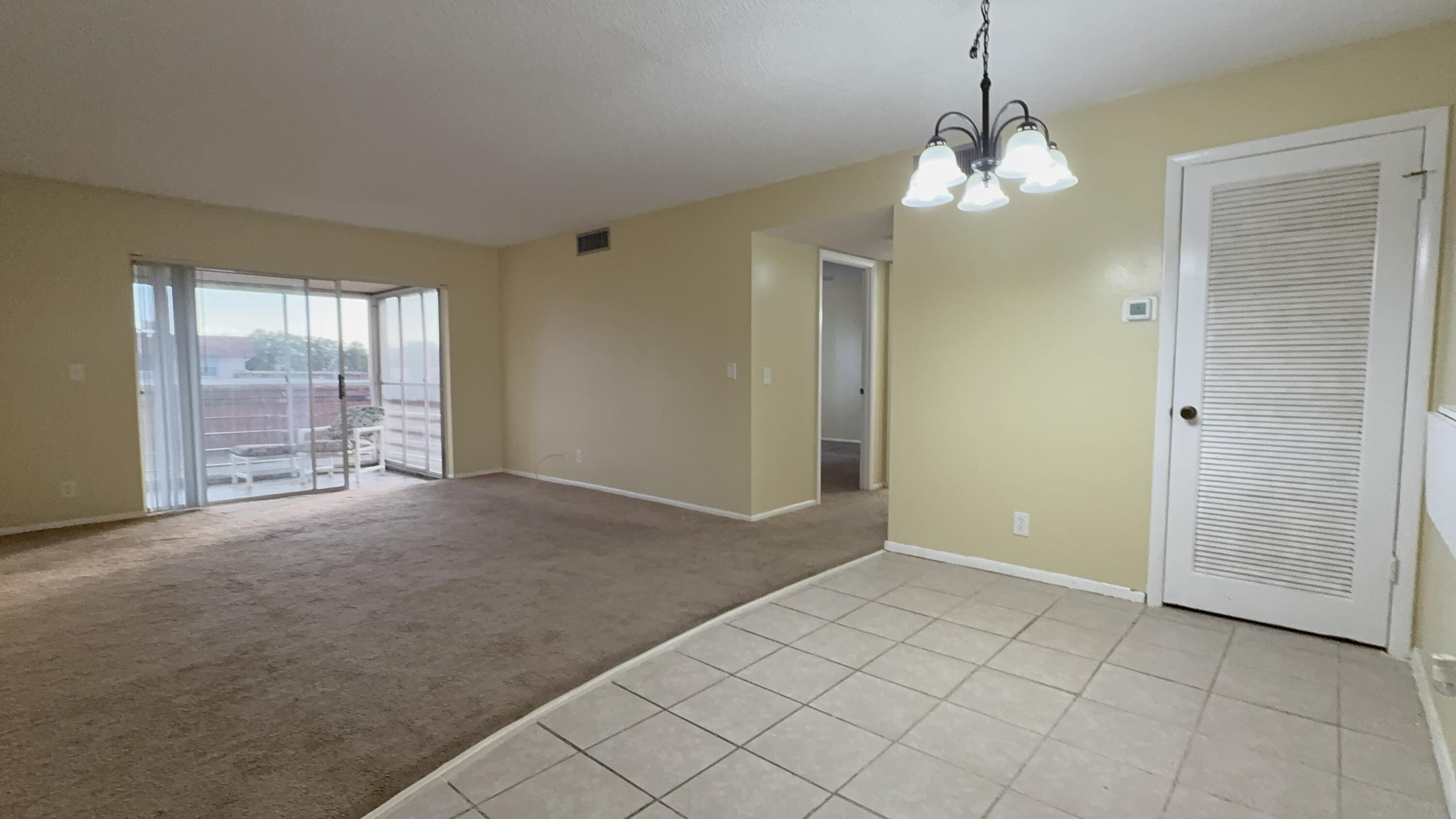 12009 Poinciana Boulevard, Unit 202 Royal Palm Beach, FL 33411 - Photo 7 of 24 an empty room with chandelier and windows
