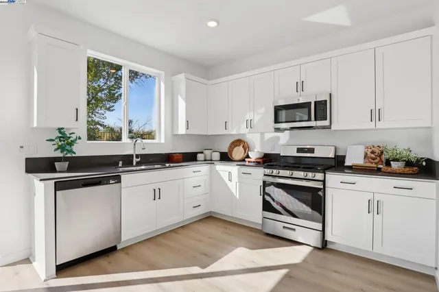 a kitchen with stainless steel appliances white cabinets a sink and a stove