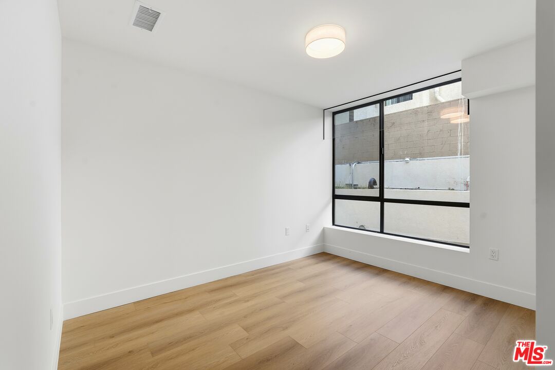 1822 Overland Avenue, Unit 103 Los Angeles, CA 90025 - Photo 4 of 10 an empty room with wooden floor and windows