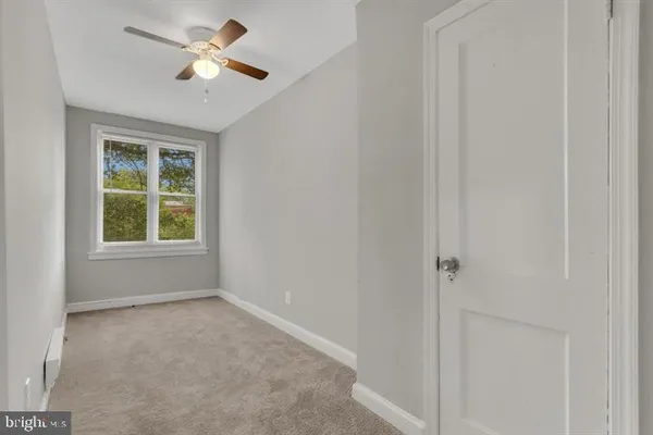 an empty room with a window and a fan