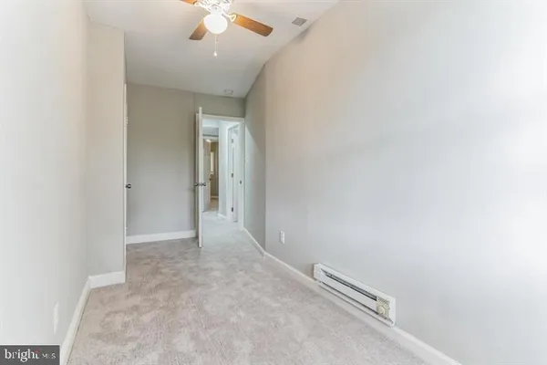 an empty room with chandelier fan and windows
