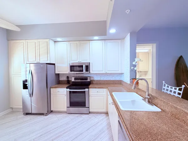 a kitchen with granite countertop a refrigerator stove and sink