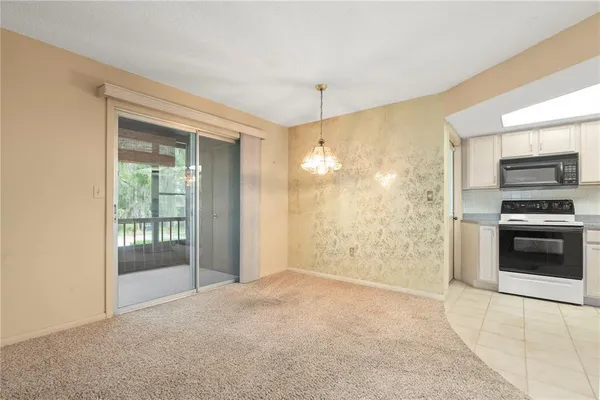 an empty room with a chandelier fan and windows