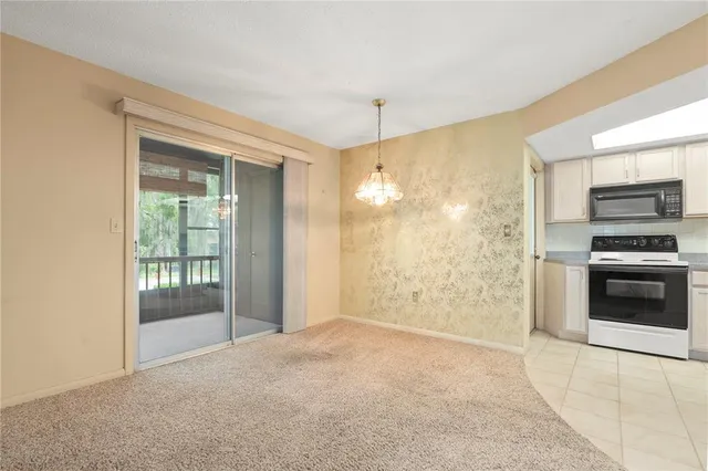 an empty room with a chandelier fan and windows