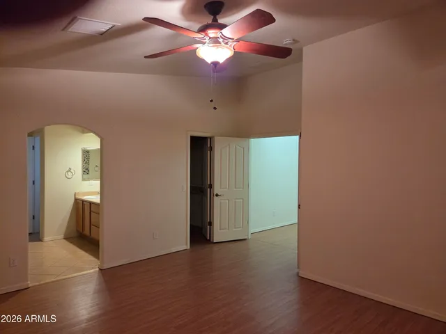 an empty room with wooden floor and a ceiling fan