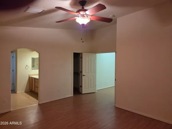an empty room with wooden floor and a ceiling fan