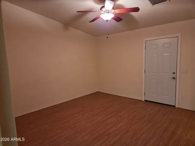 an empty room with wooden floor fan and windows