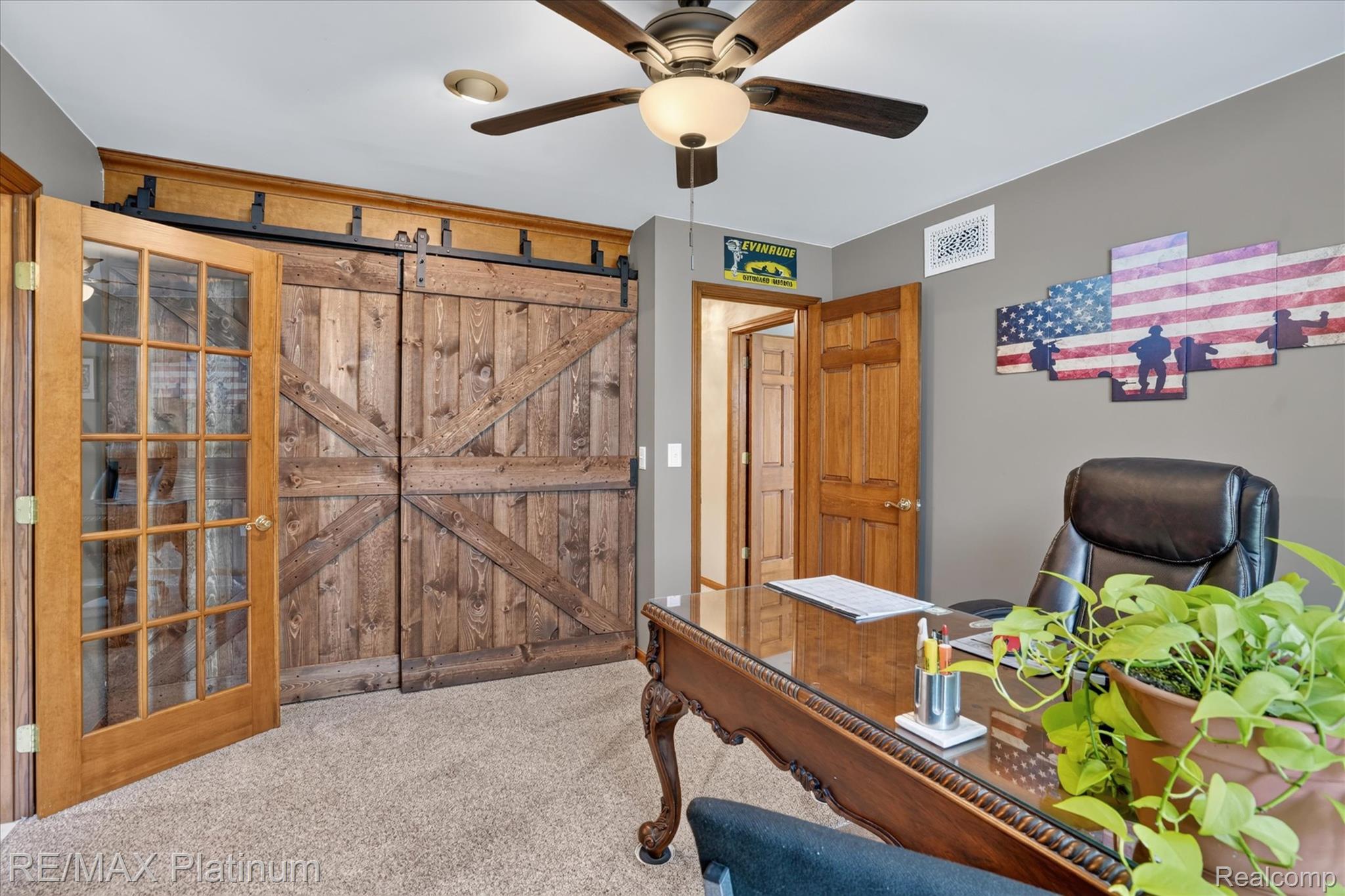 4457 Bradley Road Gregory, MI 48137 - Photo 71 of 79 Rustic barn doors with dark hardware, a ceiling fan with integrated lighting, a wood-finish door with glass panels, and neutral-toned carpeting