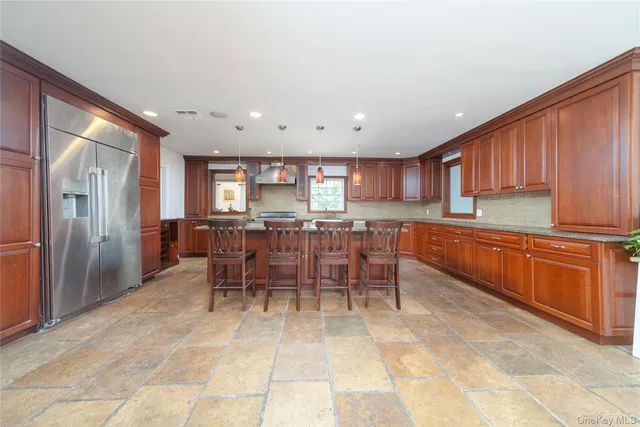 a kitchen with stainless steel appliances kitchen island granite countertop a refrigerator and cabinets