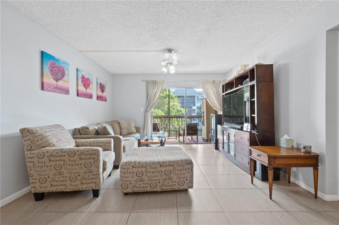 721 North Pine Island Road, Unit 302 Plantation, FL 33324 - Photo 9 of 25 a living room with furniture a flat screen tv and a floor to ceiling window