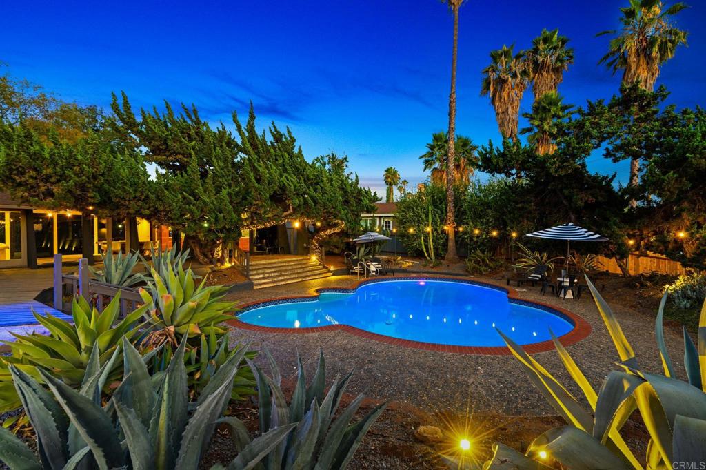 754 El Rancho Drive El Cajon, CA 92019 - Photo 1 of 55 a view of a swimming pool with lawn chairs under an umbrella and palm trees