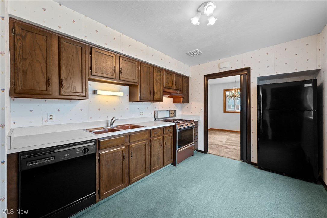 29776 Arthur Road Wickliffe, OH 44092 - Photo 12 of 49 Kitchen with black appliances, wallpapered walls, light carpet, light countertops, and under cabinet range hood