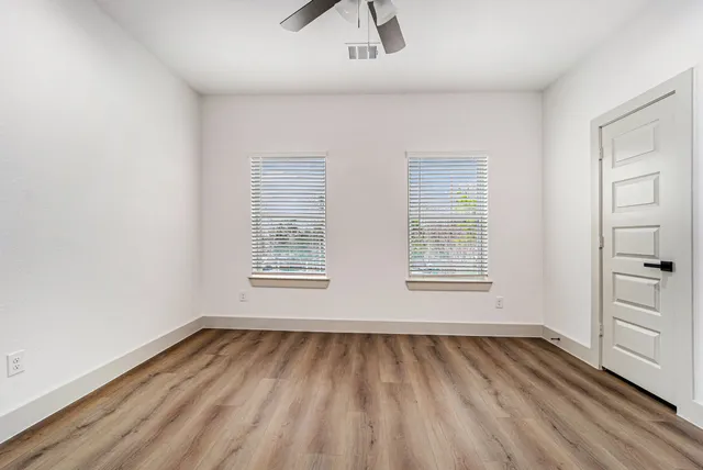 an empty room with a hardwood and windows