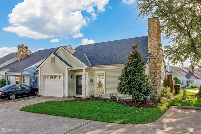 a view of a white house next to a yard with big trees