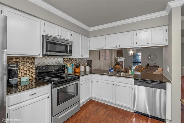 a kitchen with white cabinets a sink stove and microwave
