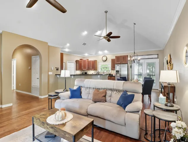 a living room with furniture kitchen view and a chandelier