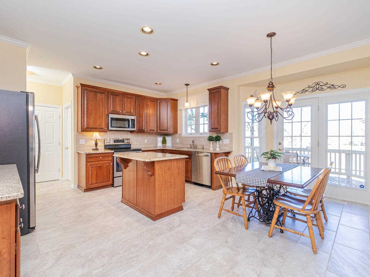 426 Seastone Street Raleigh, NC 27603 - Photo 12 of 30 a kitchen with stainless steel appliances kitchen island granite countertop a refrigerator a stove a sink a dining table and chairs
