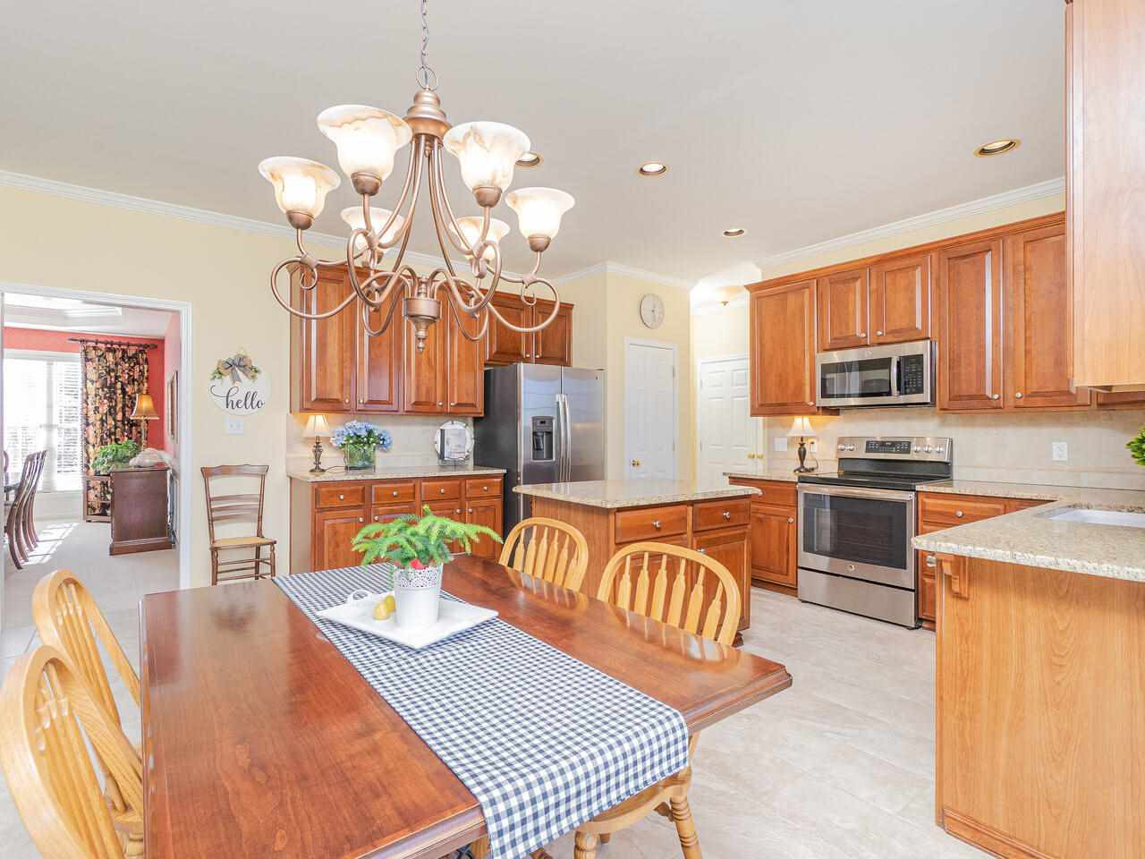 426 Seastone Street Raleigh, NC 27603 - Photo 13 of 30 a kitchen with stainless steel appliances granite countertop a stove top oven a sink dishwasher a dining table and chairs with wooden floor