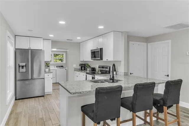 a kitchen with stainless steel appliances granite countertop a refrigerator a stove a sink a dining table and chairs