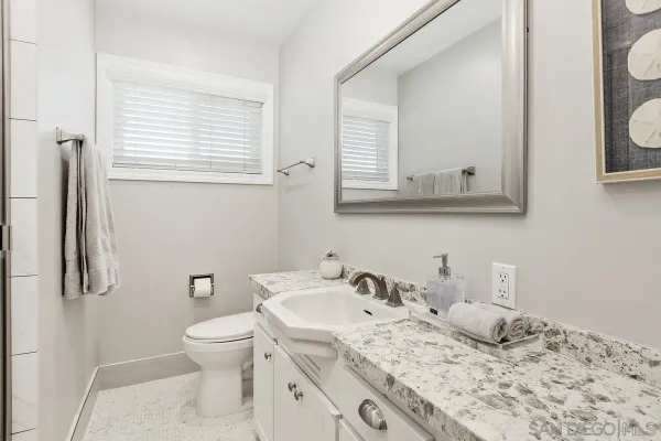 a bathroom with a granite countertop sink toilet and mirror