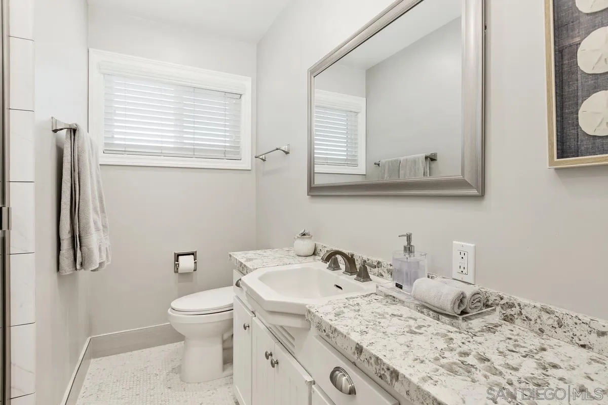 852 Olive Avenue Coronado, CA 92118 - Photo 11 of 12 a bathroom with a granite countertop sink toilet and mirror